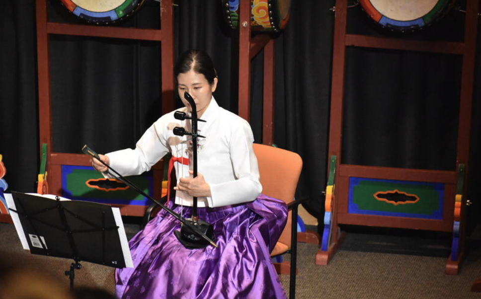 A woman plays a traditional Korean musical instrument