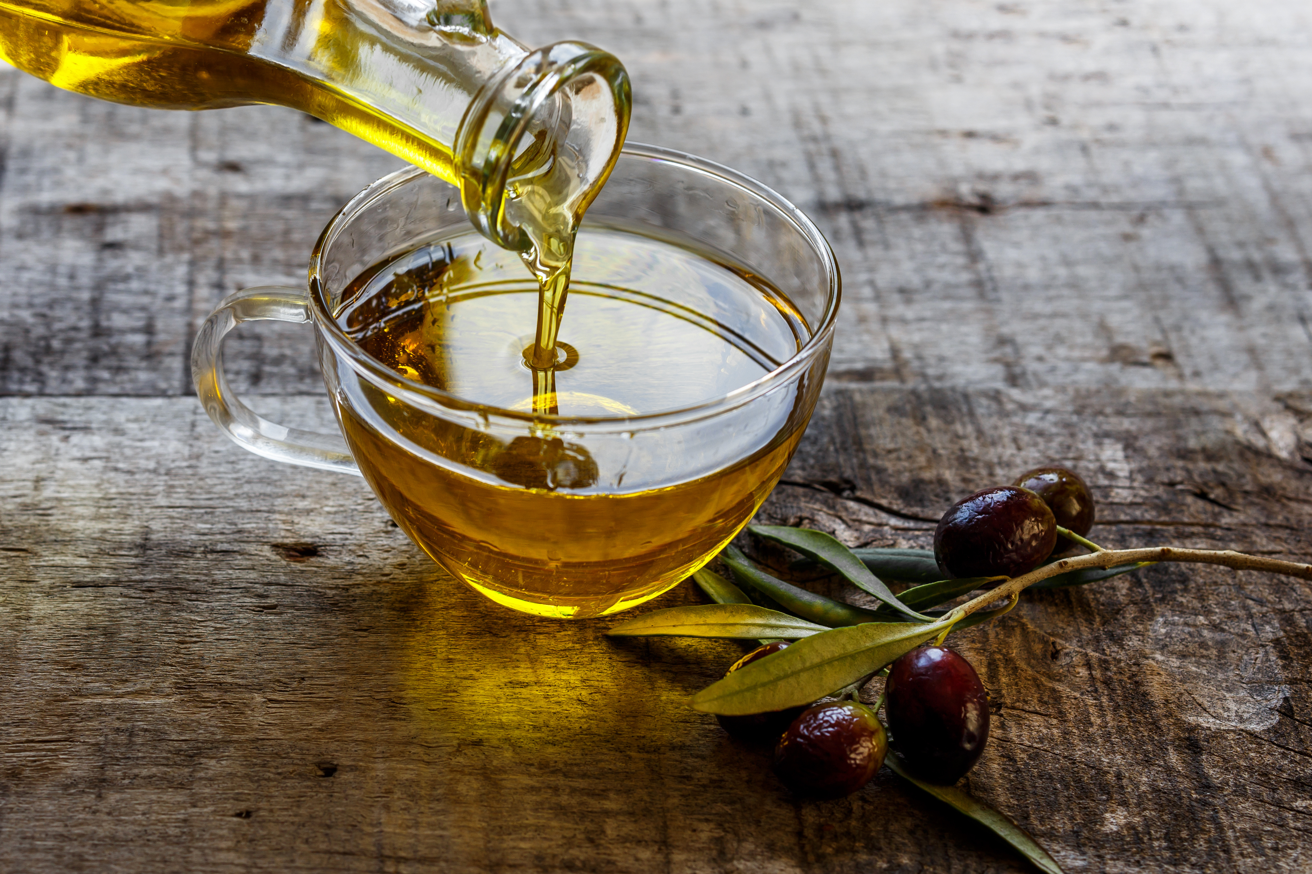 Olive oil pouring into glass bowl