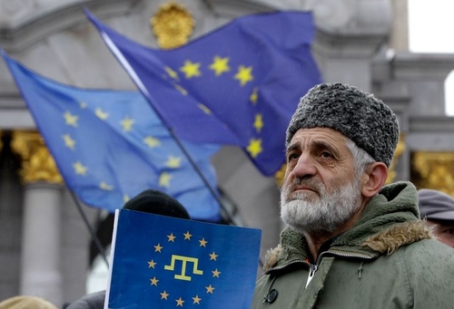 A demonstrator holds an EU flag with a Crimean Tatar symbol in its center, Kyiv, Nov. 29, 2013. PHOTO: SERGEI CHUZAVKOV/ASSOCIATED PRESS
