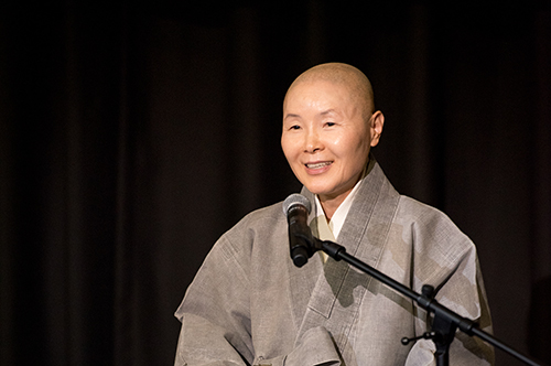 A close-up of Venerable Jeongmok speaking in front of a microphone