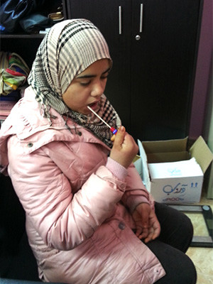 A young woman provides a DNA sample via cheek swab. She was among a cohort of Syrian adolescents forcibly displaced by conflict to participate in a study on the effects of genetic and resilience on the mental health recovery. (Photo courtesy of the research team.)