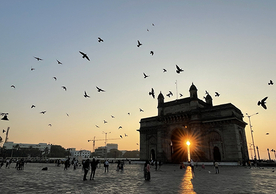 Bird fly over a courtyard and historic building in India at sunset