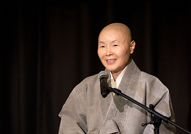 A close-up of Venerable Jeongmok speaking in front of a microphone