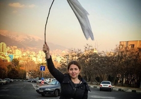 A young Iranian woman waves a white headscarf in protest of her country’s compulsory hijab rule.