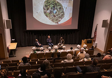 A view of the three speakers in front of an aerial photograph of an Ethiopian church forest in Luce Hall auditorium