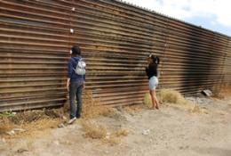 two people staring at a metal fence
