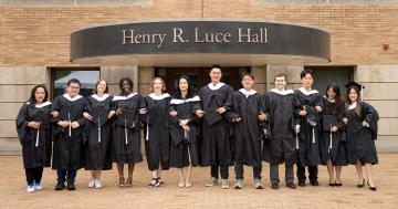 The MacMillan Center's 12 master's degree graduates pose in front of Luce Hall in May 2024
