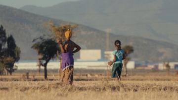 Farmer Workinesh Chala and her daughter Rehoboth standing in the fields of Dibdibbe Village, looking out towards the Eastern Industry Park, Oromia region, Ethiopia.