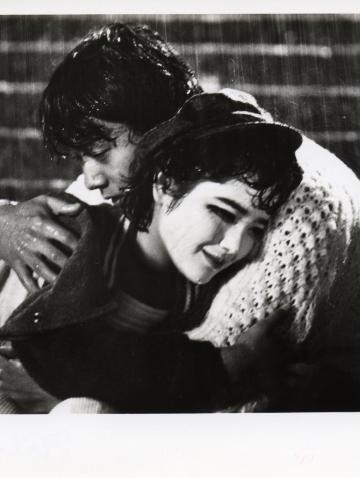 A man and woman embrace one another seated on stairs