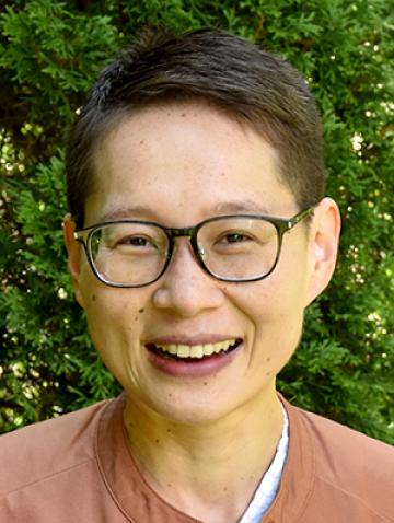 Sunny Xiang smiling headshot in front of green bush