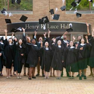 The MacMillan Center's master's degree graduates celebrate by throwing their graduation caps in the air in front of Luce Hall in May 2023