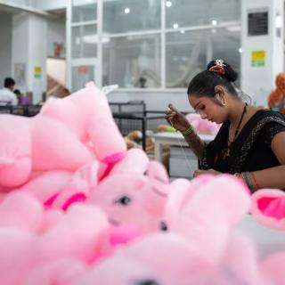 A worker is sewing pink stuffed animals 