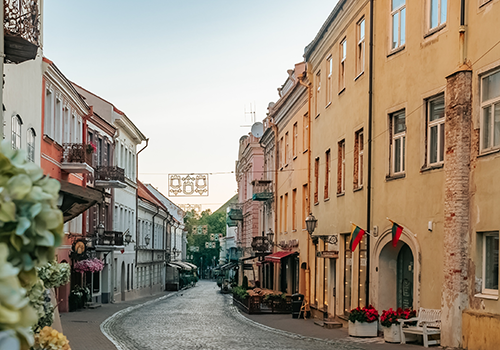 A view of a historic street in Vilnius, with Lithuanian flags hanging on either side of the doorway